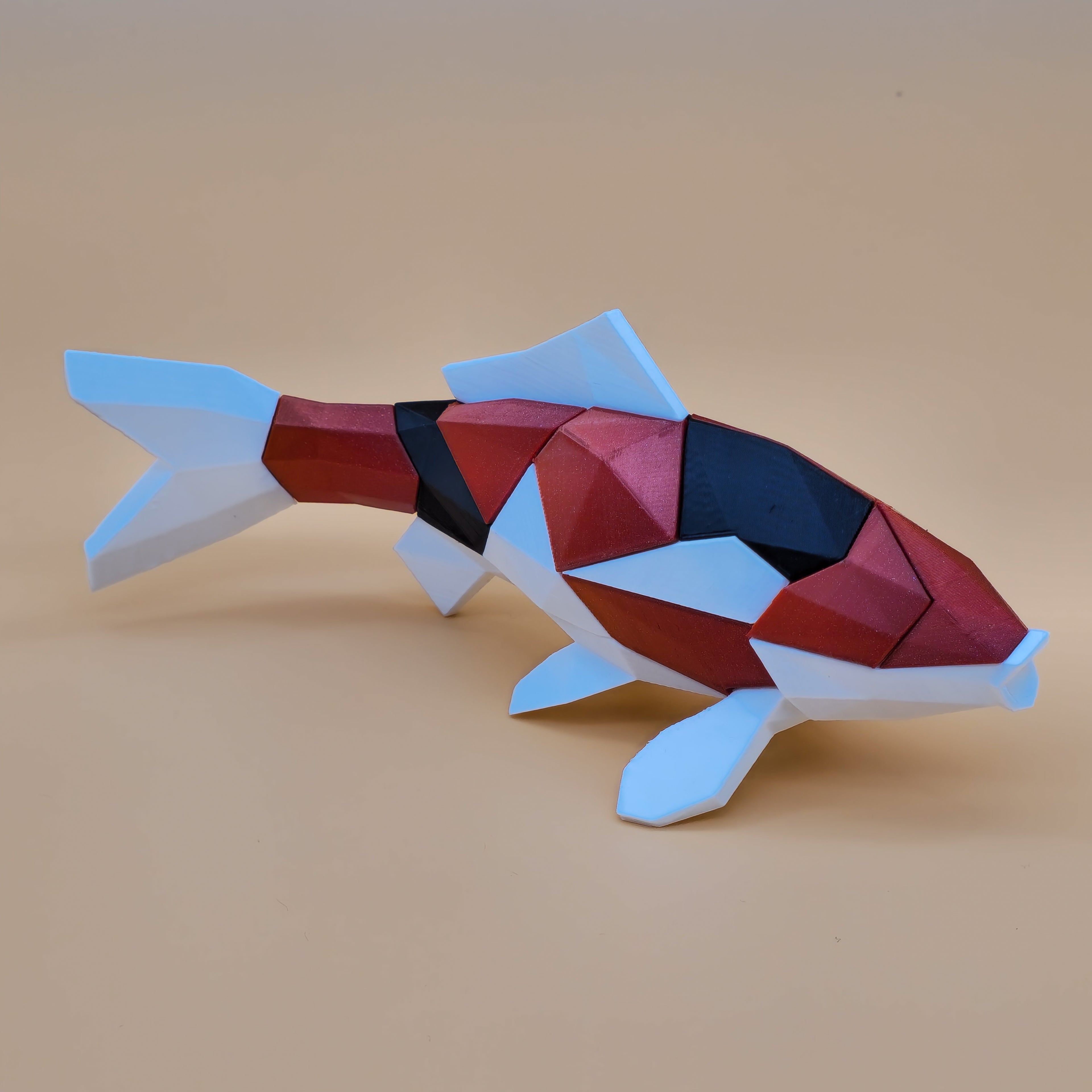 Red, black and white 3D printed magnetic koi puzzle on a beige background