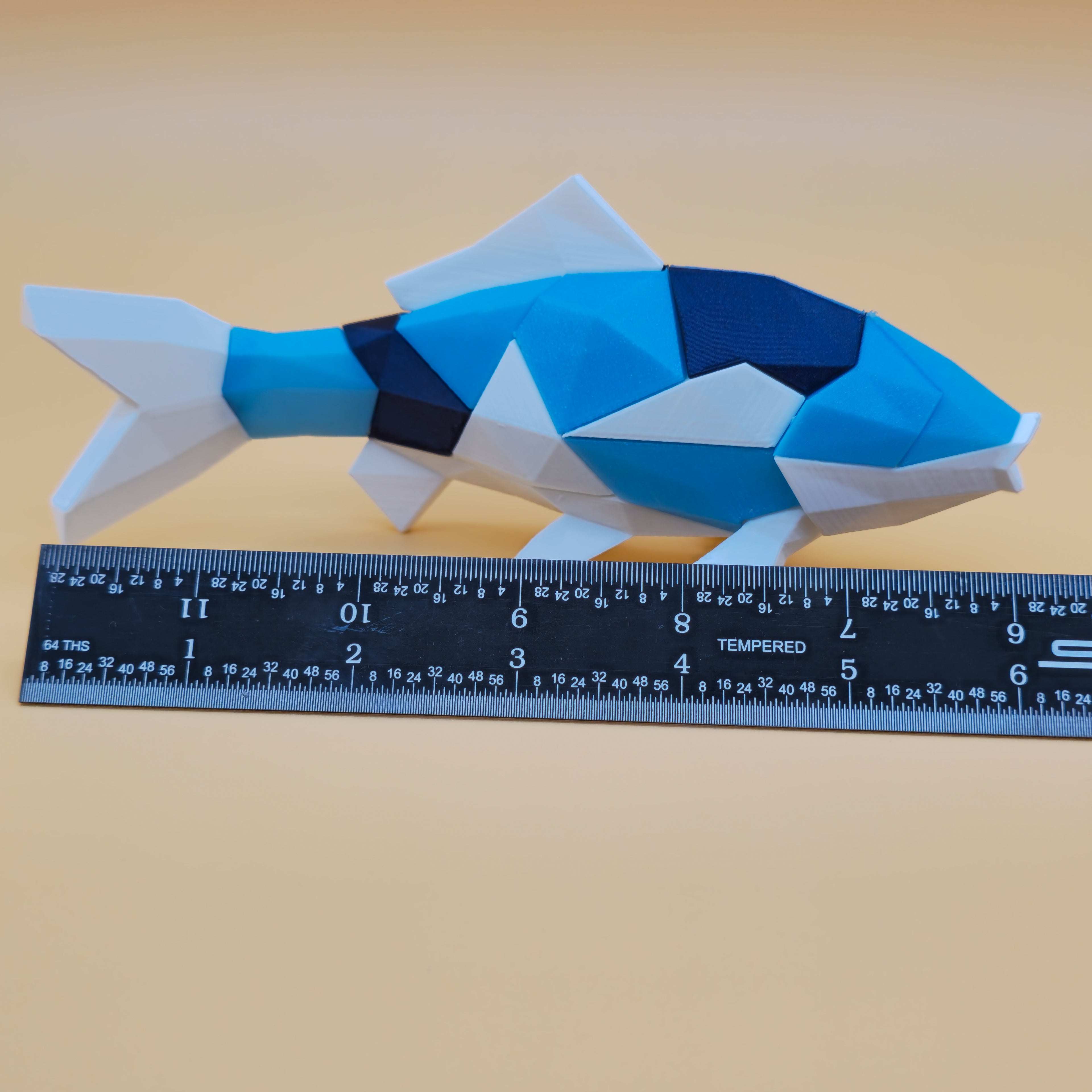 Koi magnetic 3D printed puzzle with blue and white pattern on a beige background, ruler for scale.