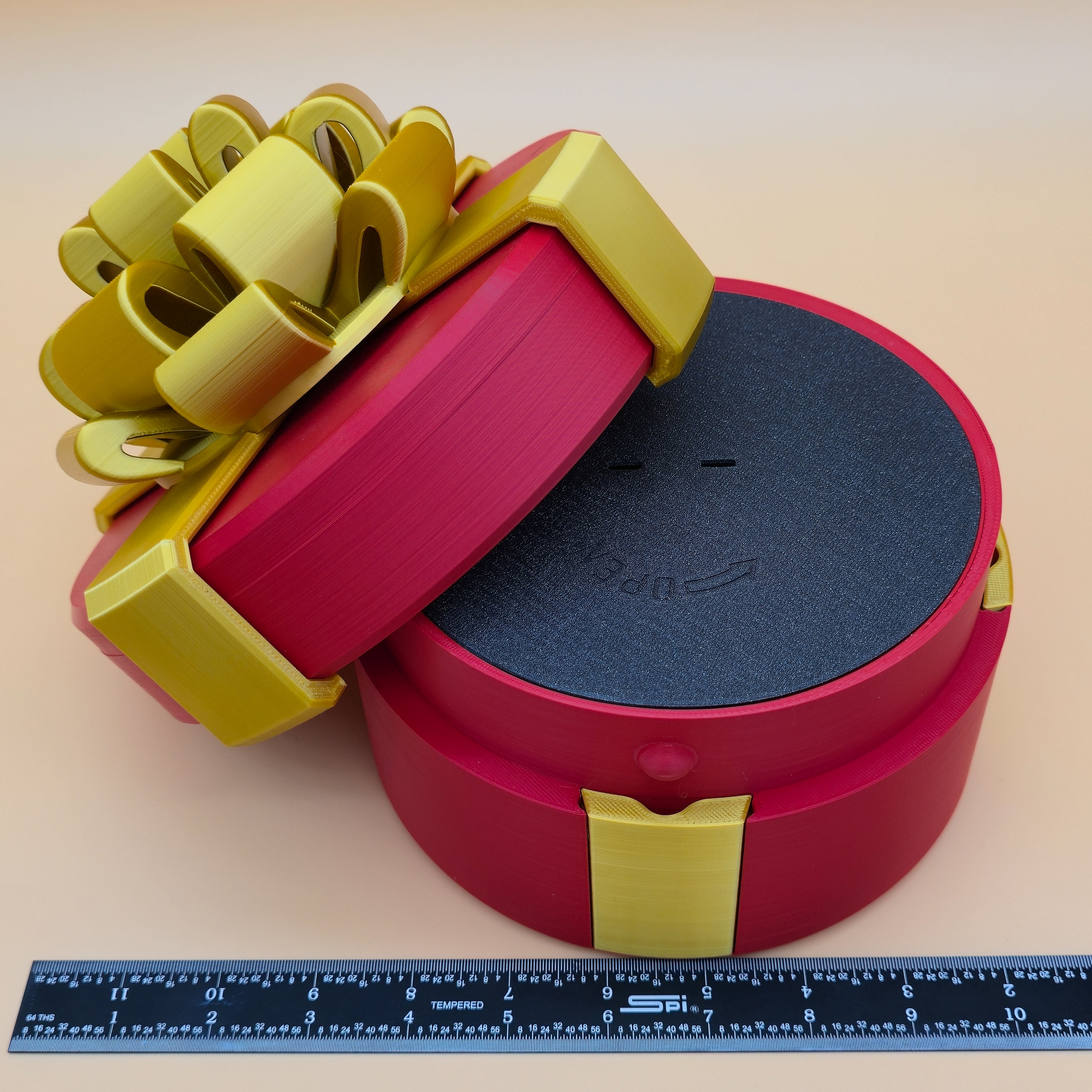 Red nested gift box with a gold bow and black insert, accompanied by a ruler for scale.