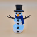 3D-printed snowman puzzle with a black top hat, blue scarf, and carrot nose on a beige background.